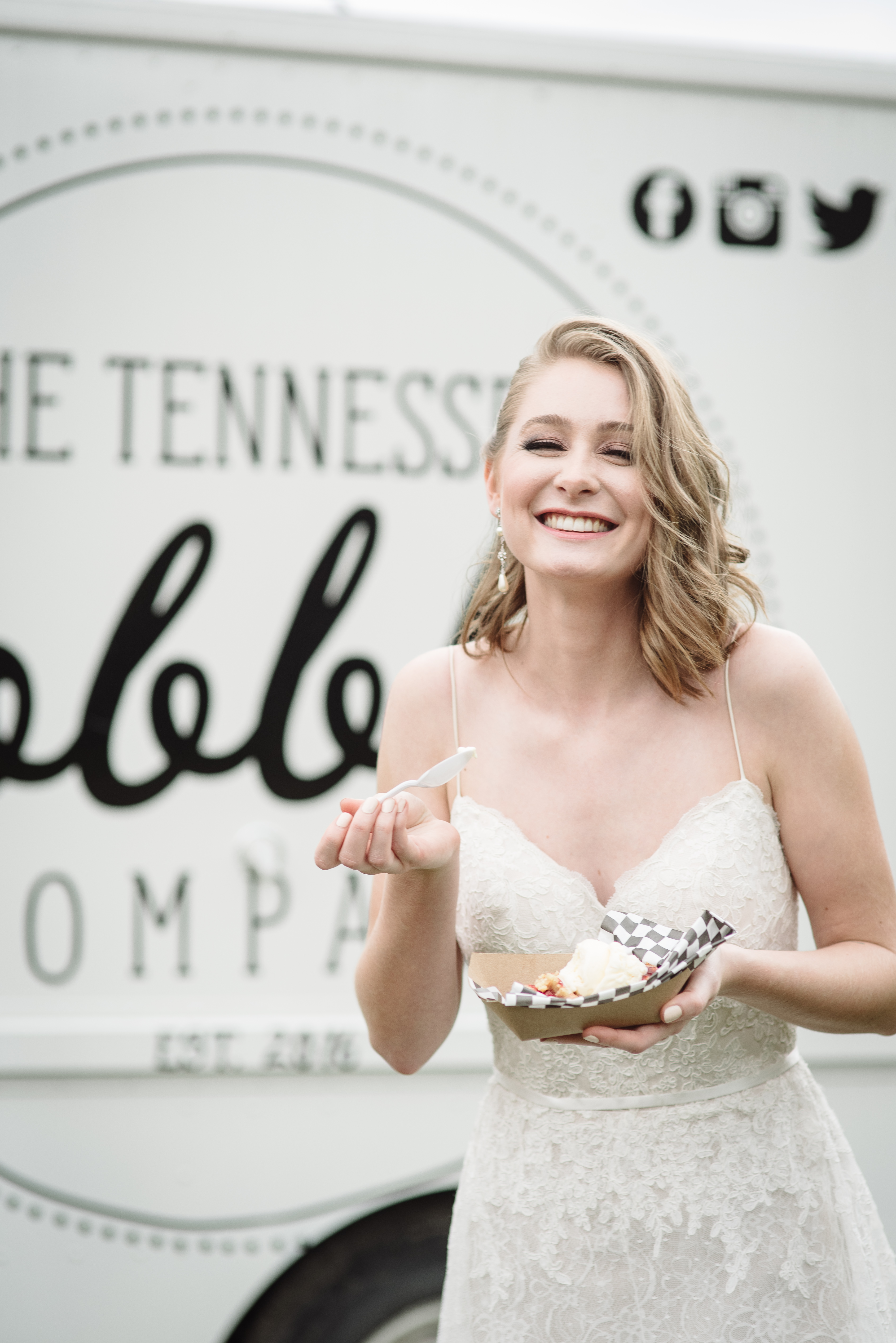 A happy bride is eating peach cobbler for her wedding day from a wedding food truck in Nashville