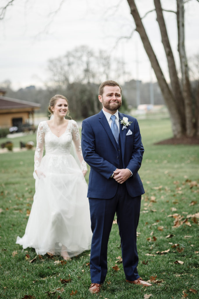 A January Bride is walking up to her husband to be for their first look and her groom is crying in the photo in Nashville, TN by Dolly DeLong Photography LLC