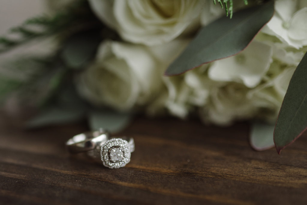 close up shot of a wedding ring beside white roses on a wedding day by Nashville Wedding Photographer Dolly DeLong Photography