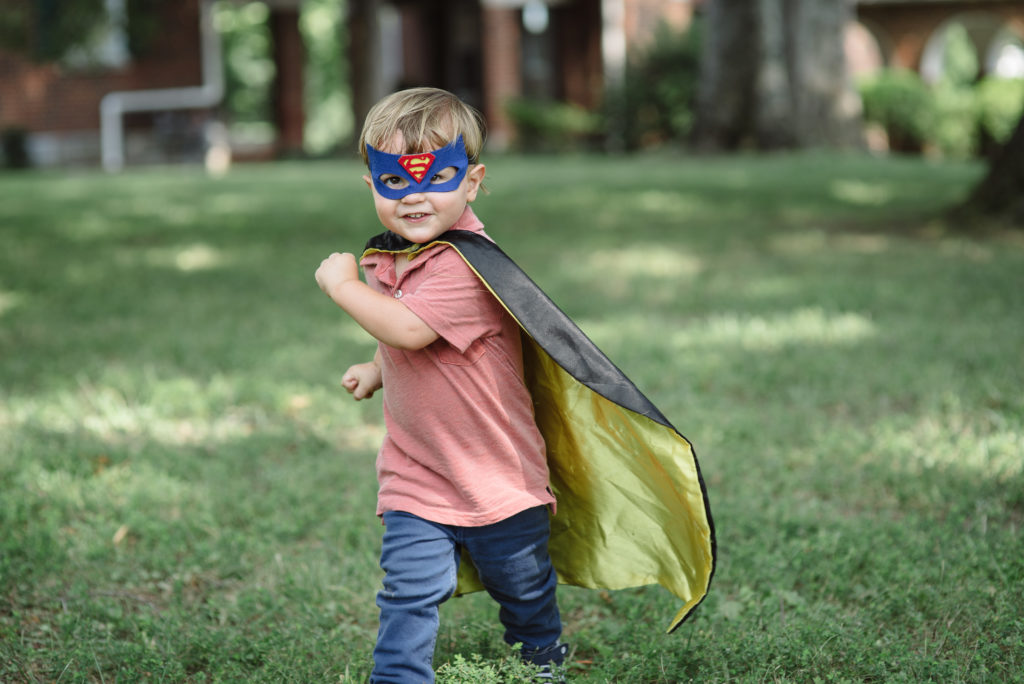 Young Boy Dressed as Superhero running in park for Family Session with Dolly DeLong Photography