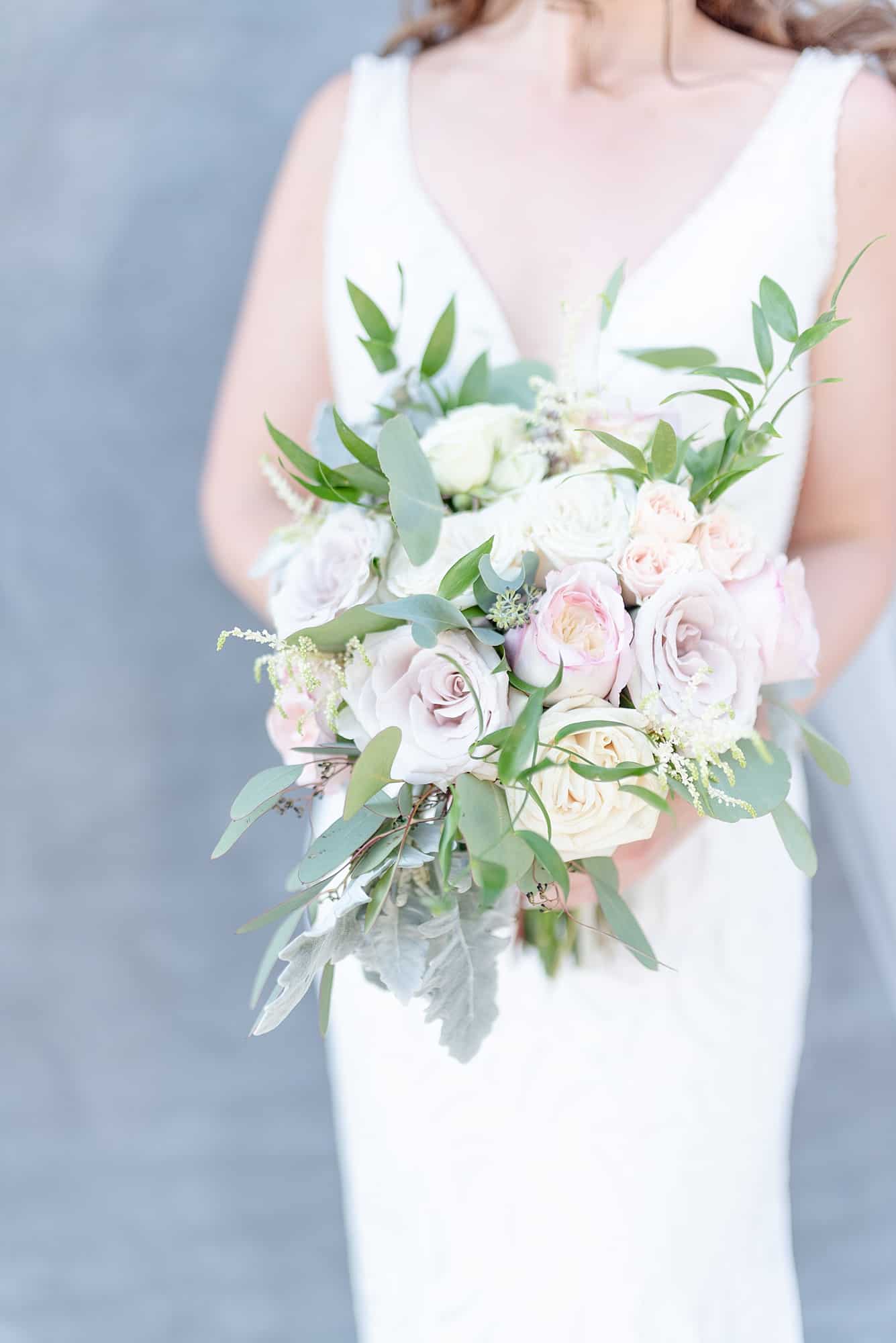 Close up shot of a bridal bouquet featuring lush colors of green pink blush and ivory on a wedding day in Nashville