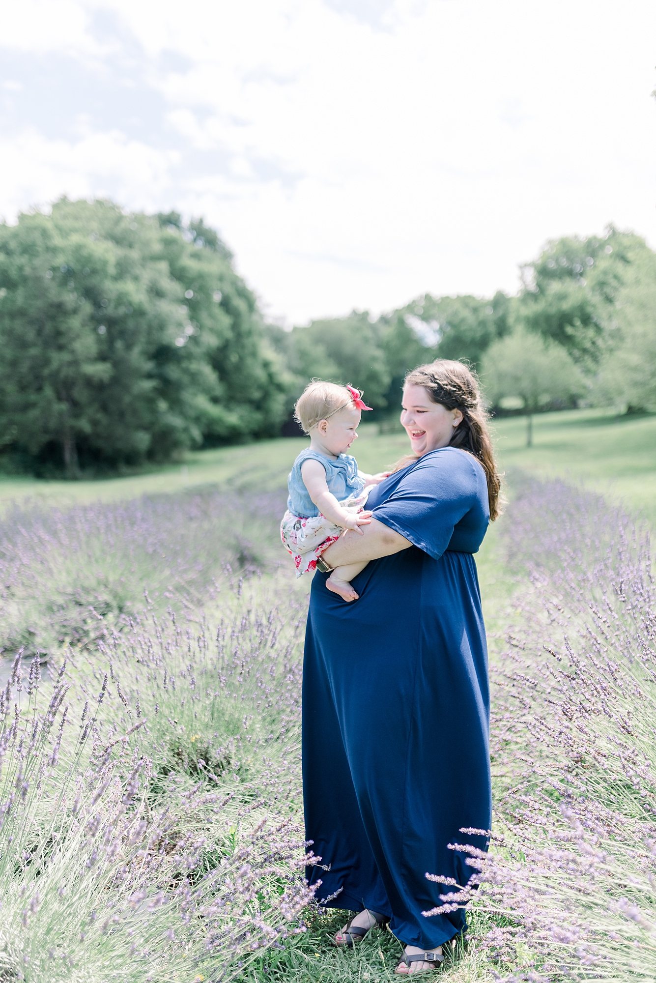 Mom holding baby girl in a lavender field in Nashville TN for girls One Year old Portrait Session Mom is smiling at daughter