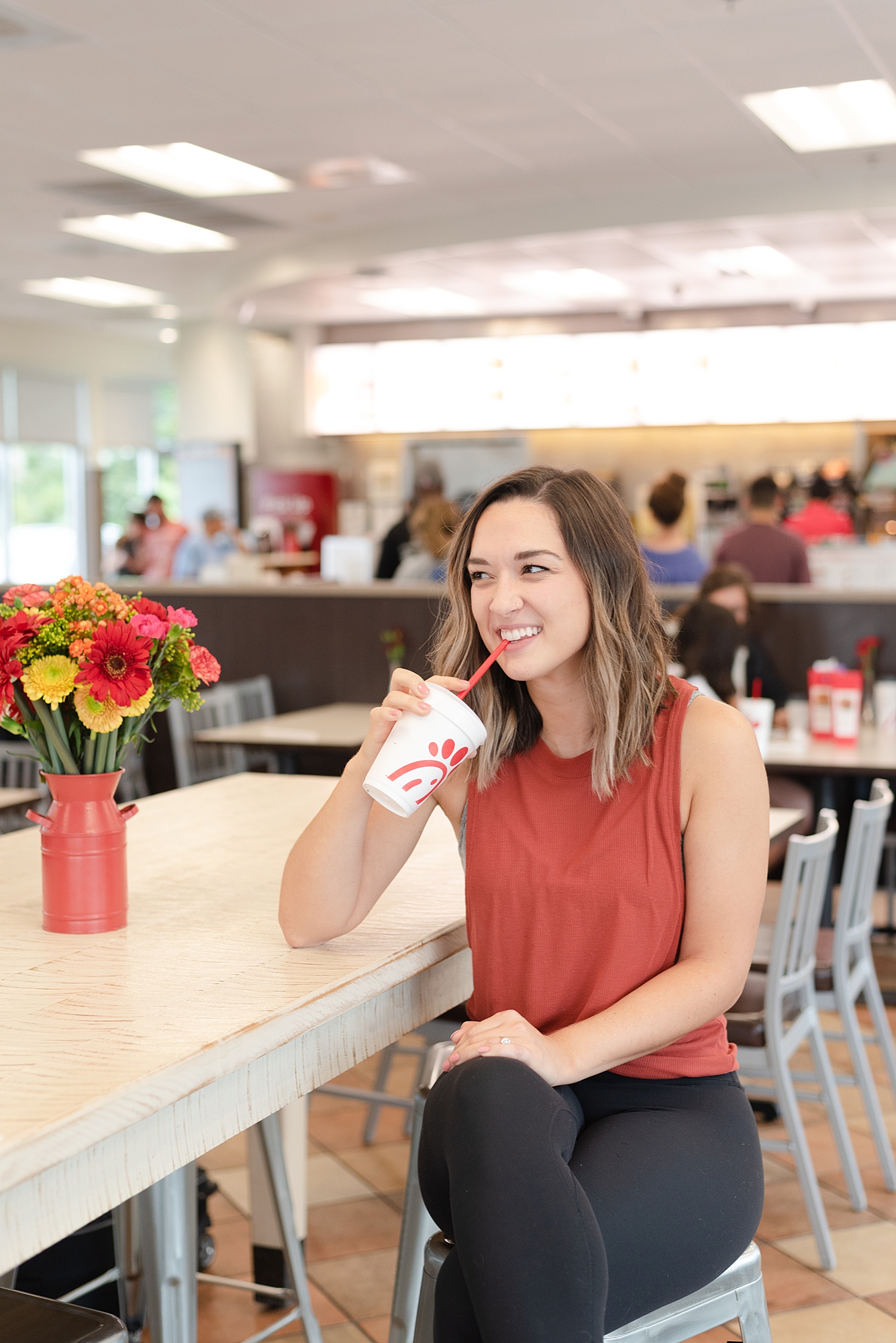 Joyful Woman Sitting in Nashville Chick Fil A drinking from her CFA cup and laughing for a branding session