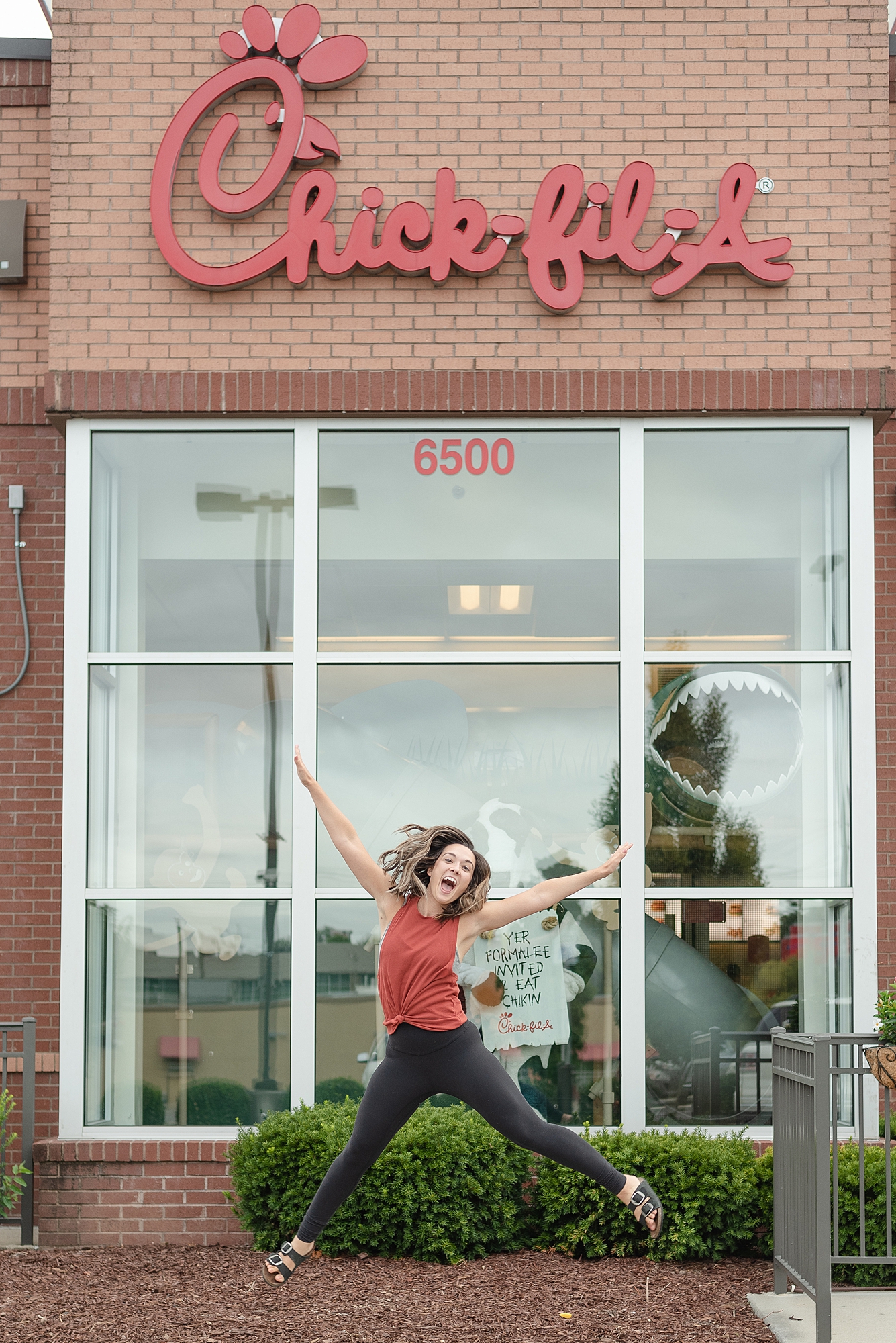 Woman jumping in front of Chick Fil A for her Branding Session in Nashville