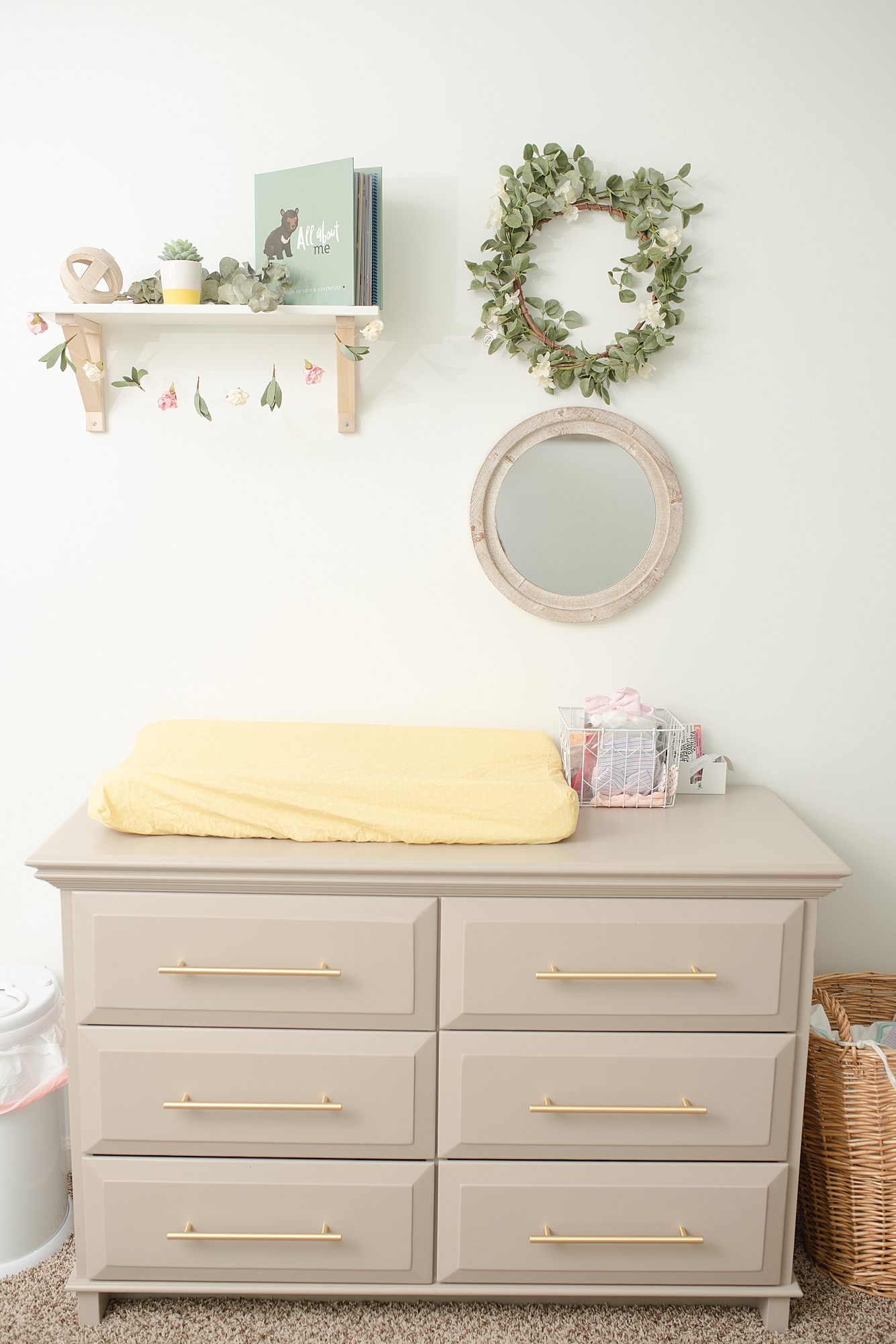 Modern Day Nursery Decor Details in a girls room a very gray changing table with a yellow changing pad and a green wreath above the changing table