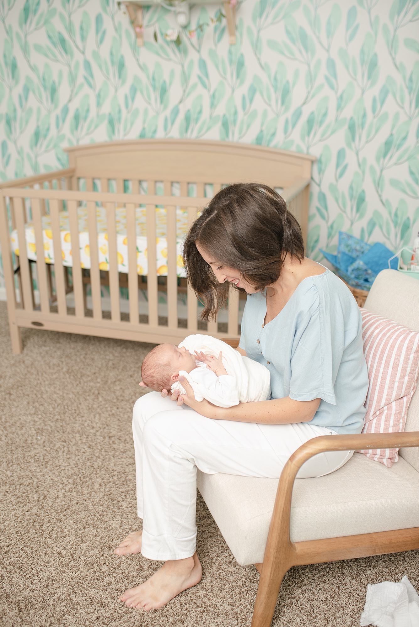 New mom is holding her baby daughter in a modern nursery