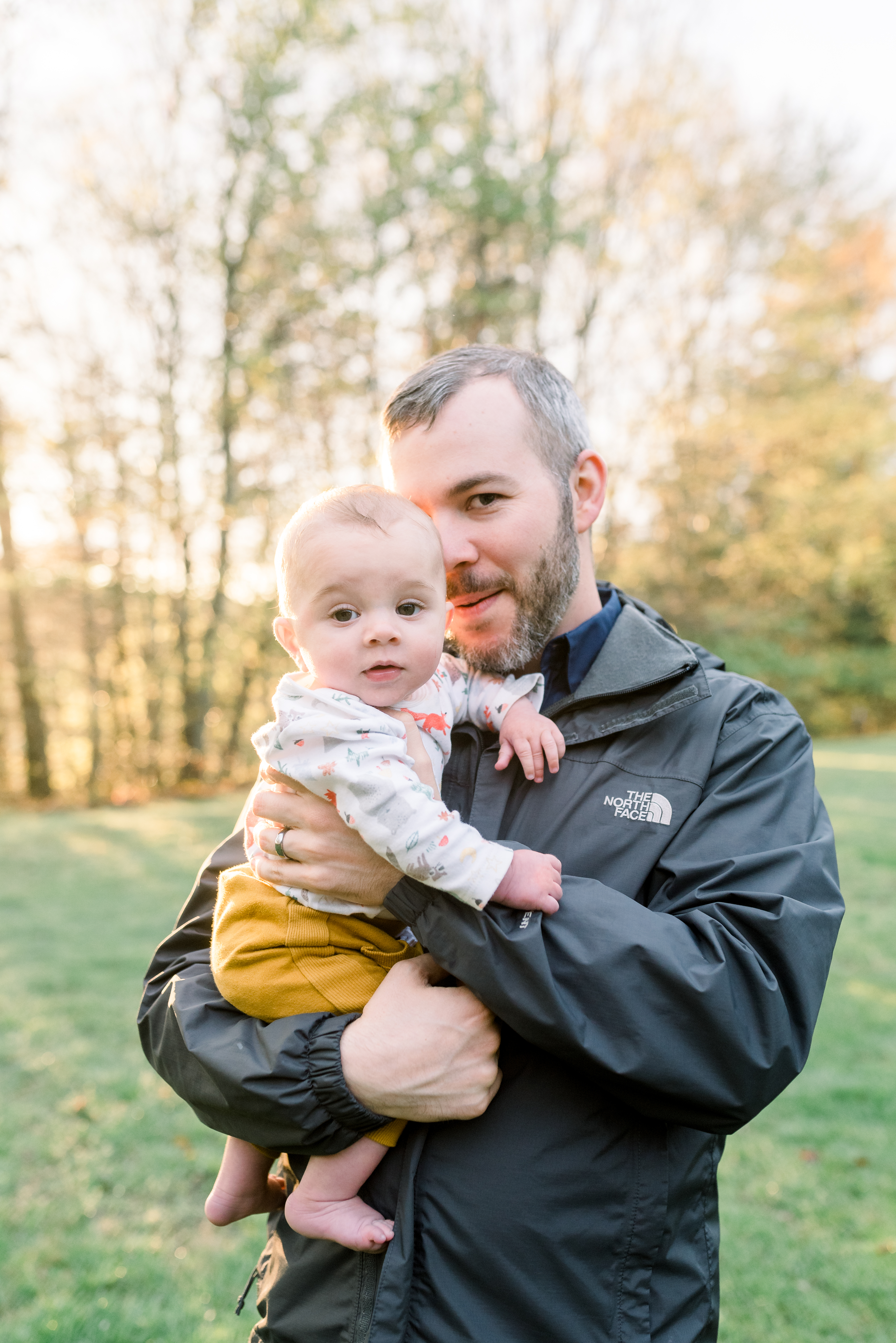 Father is holding his infant son during the golden hour of sunset in West Virginia