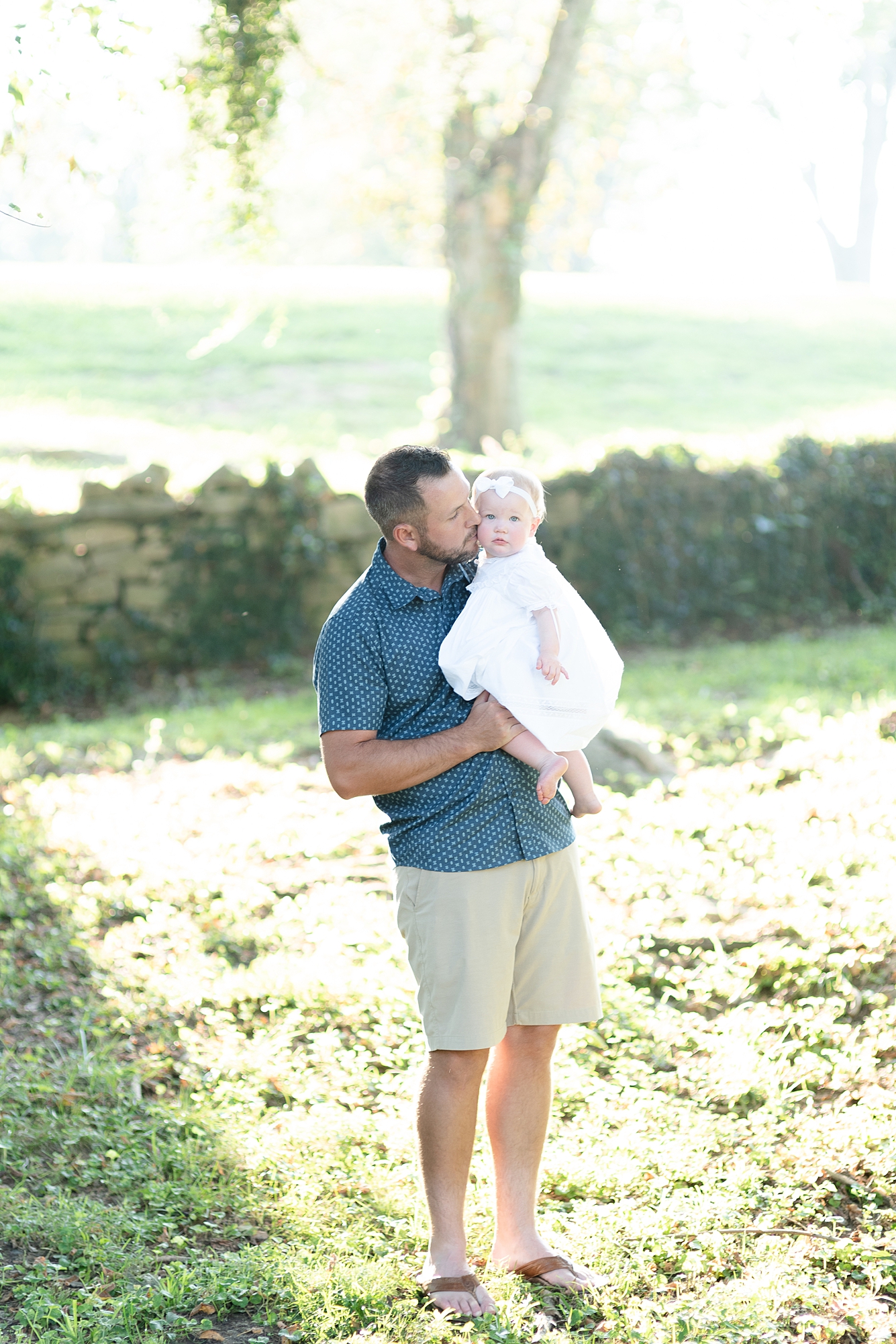Dad is kissing his baby girl for her One Year Portraits at Ravenswood Mansion