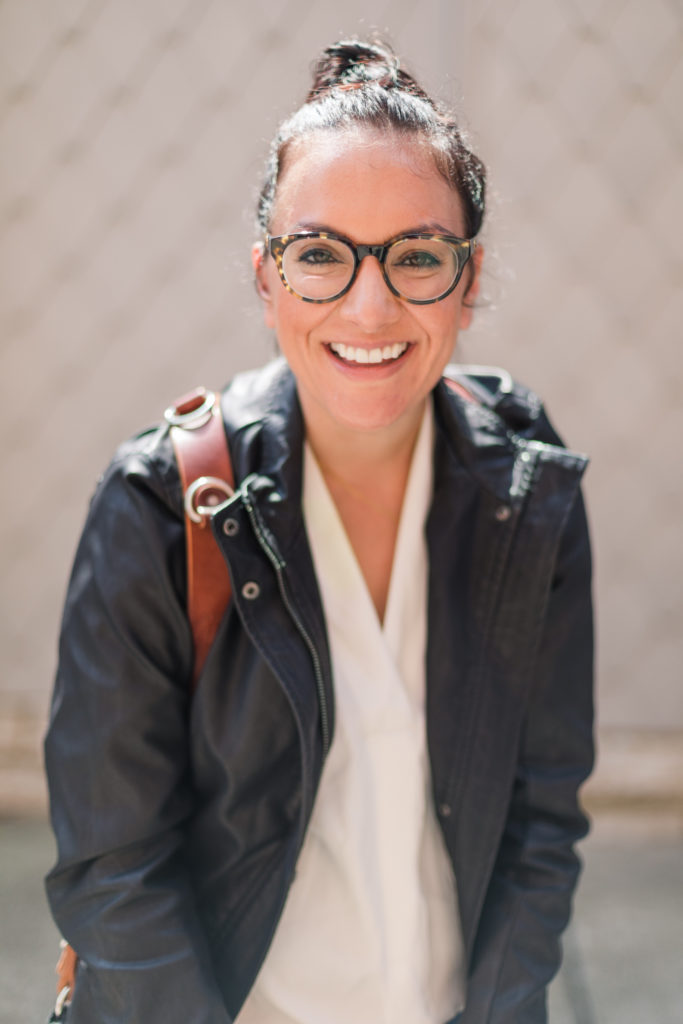 Happy Woman looking at camera and smiling she is wearing her hair in a bun and has glasses