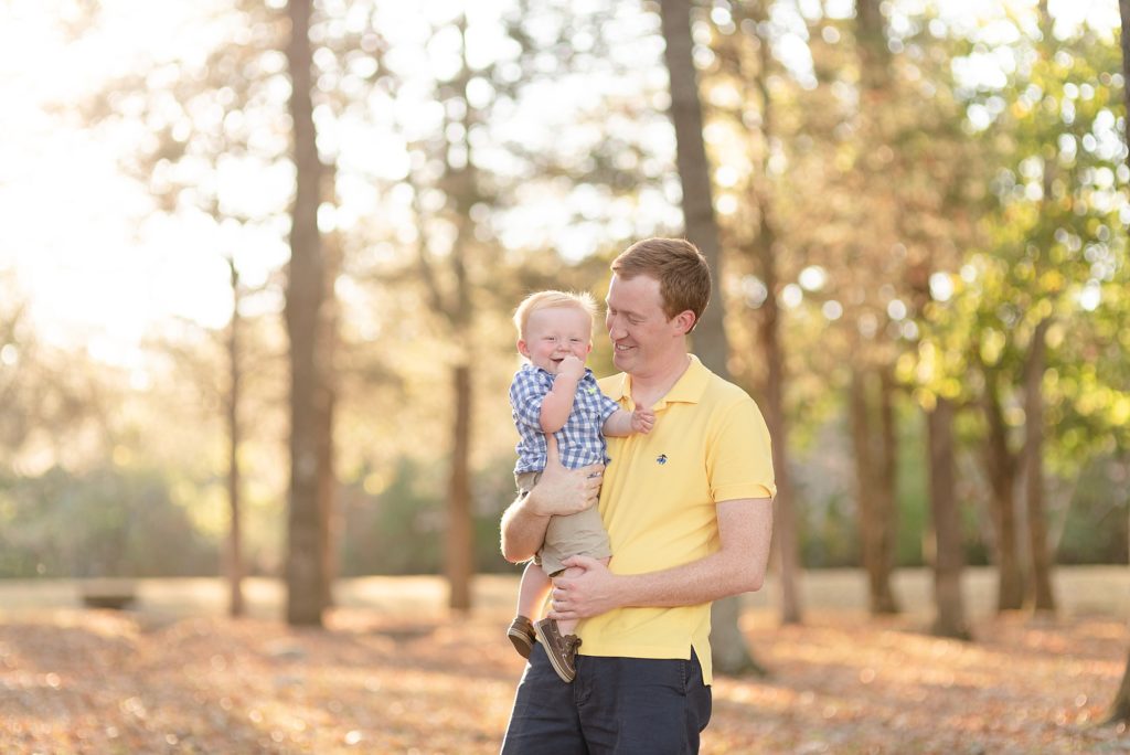Dad is lifting baby boy in air for family portraits in Nashville by Dolly DeLong Photography