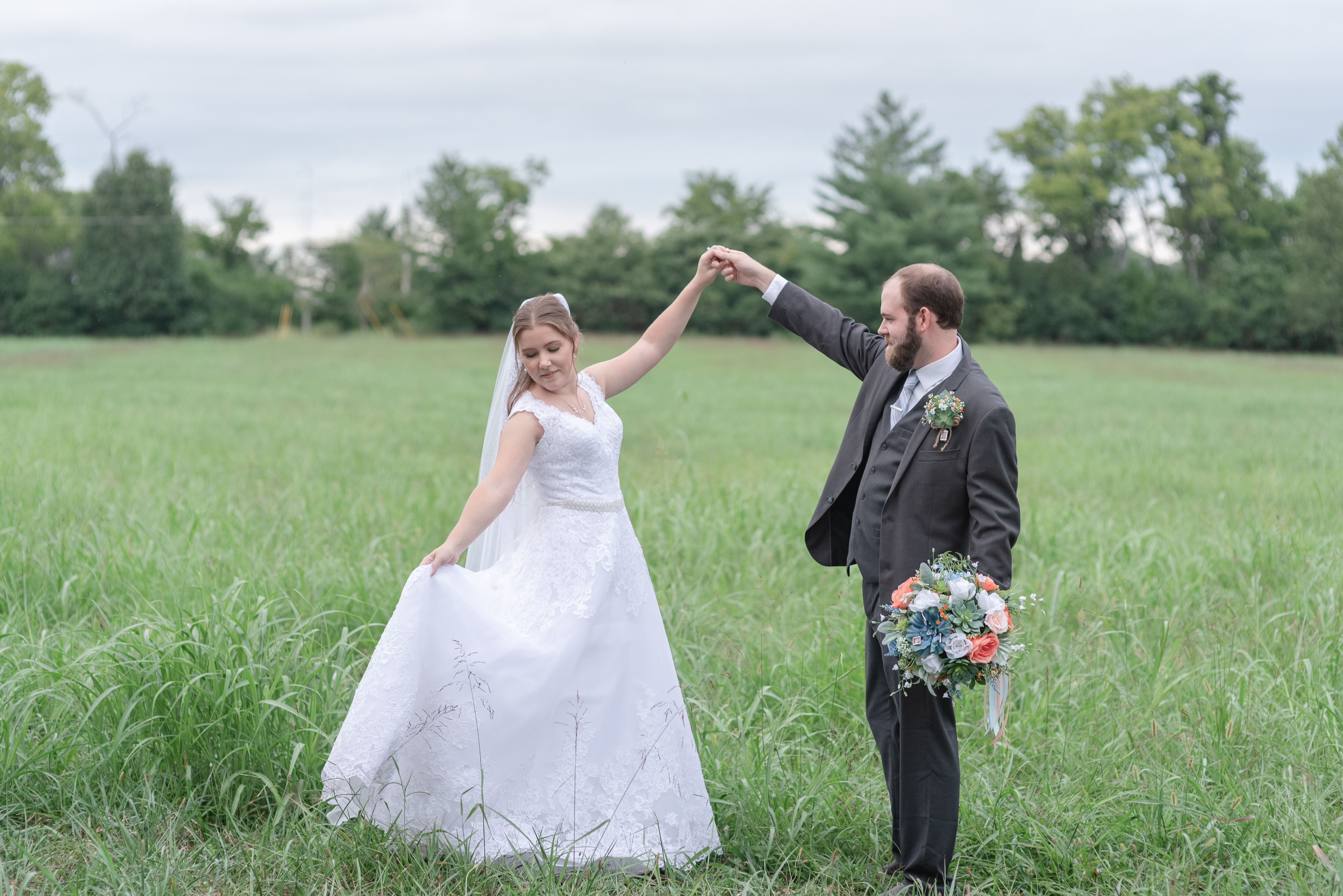 A new husband and wife are dancing together in a field in Nashville, TN