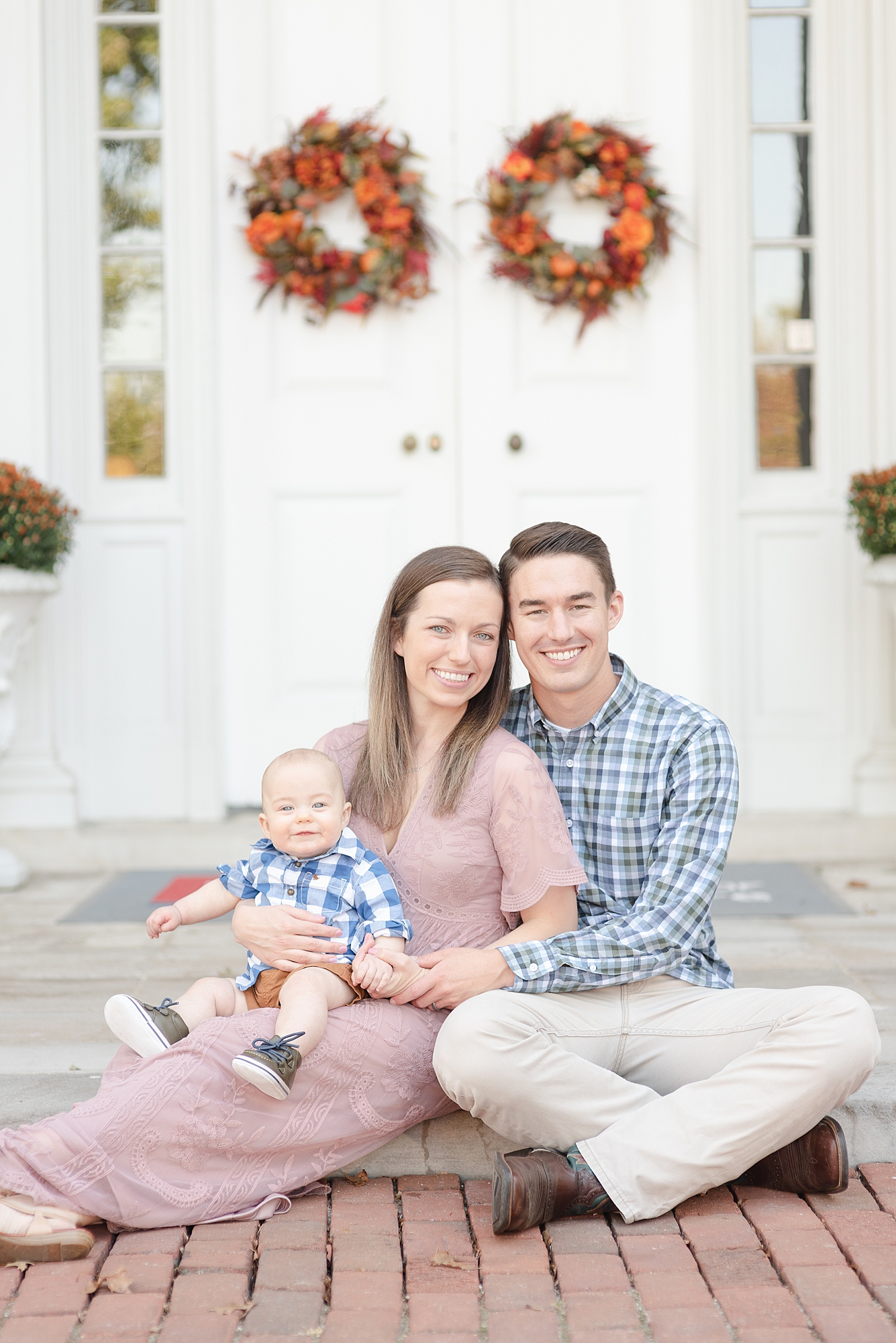 Family of three is sitting on porch and smiling at camera for family portraits in Nashville by Dolly DeLong Photography