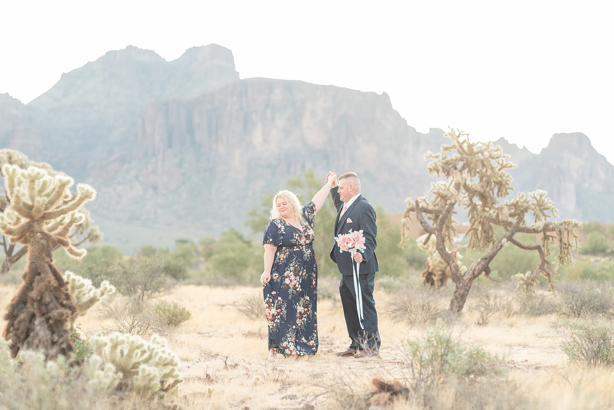 A woman is being twirled by her fiance for their sunrise arizona engagement session