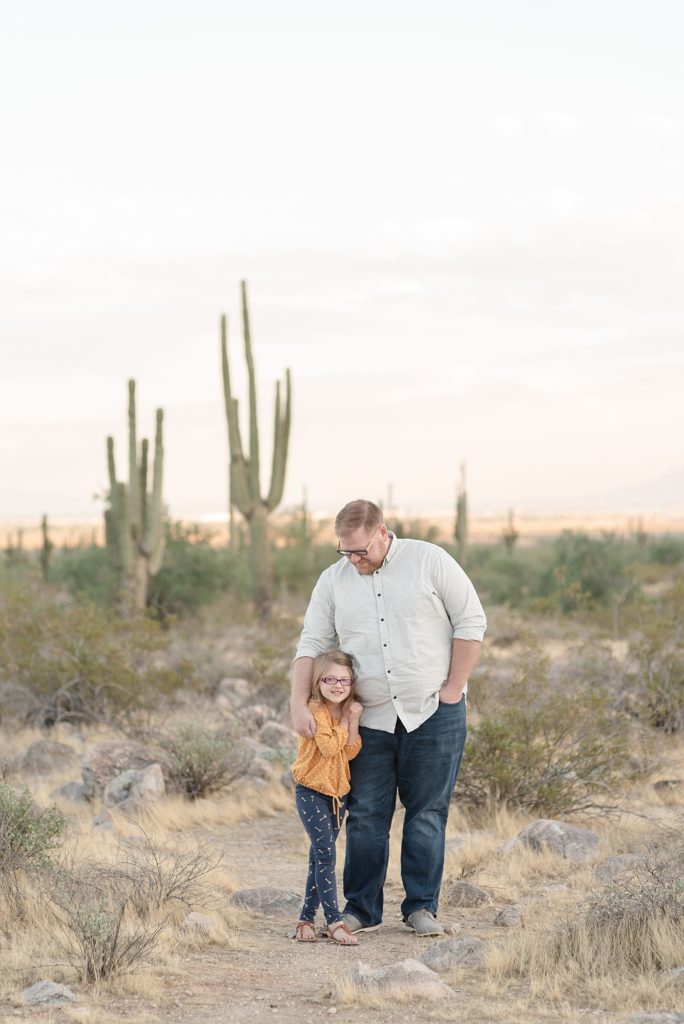 A father is looking down at his daughter in the Phoenix Arizona Desert Near the Base of the White Tank Mountains for family Christmas portraits