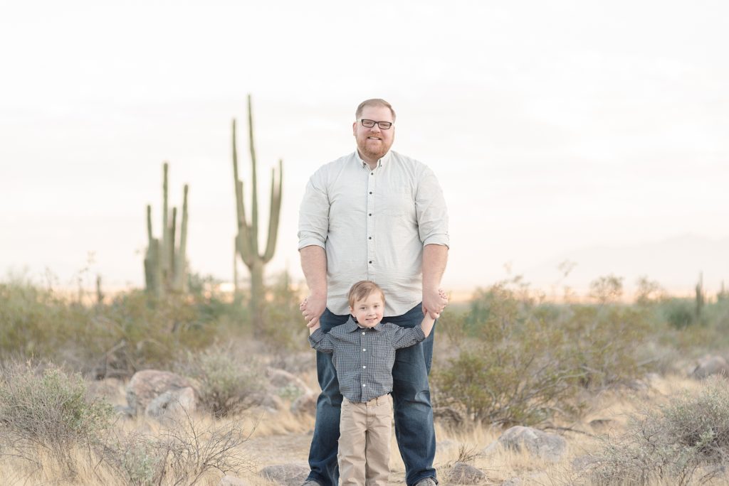 A Father is standing beside his middle son in the Phoenix Arizona Desert for christmas family portraits by Dolly DeLong Photography