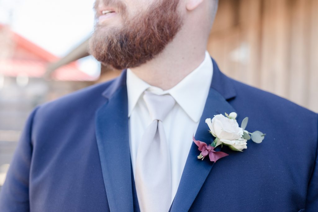 detail shot of a groom getting ready in his navy tuxedo by street tuxedo