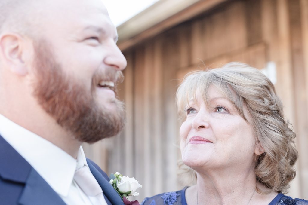 a groom's mom is looking at her son and smiling and excited for the wedding day