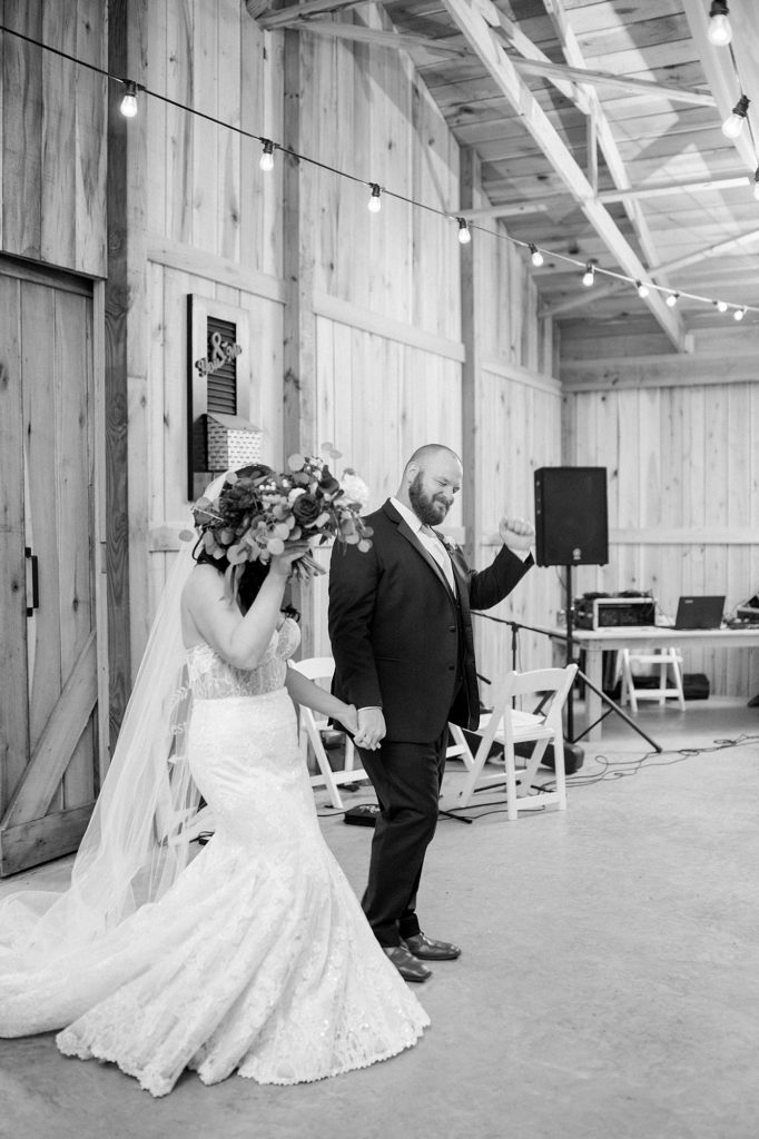 a black and white portrait of a husband and wife entering their reception