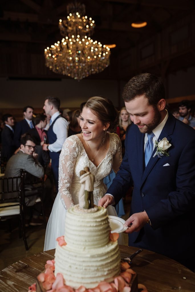 a new husband and wife are cutting their cake at their winter wedding at the barn of sycamore farms in arrington Tennessee by Dolly DeLong Photography