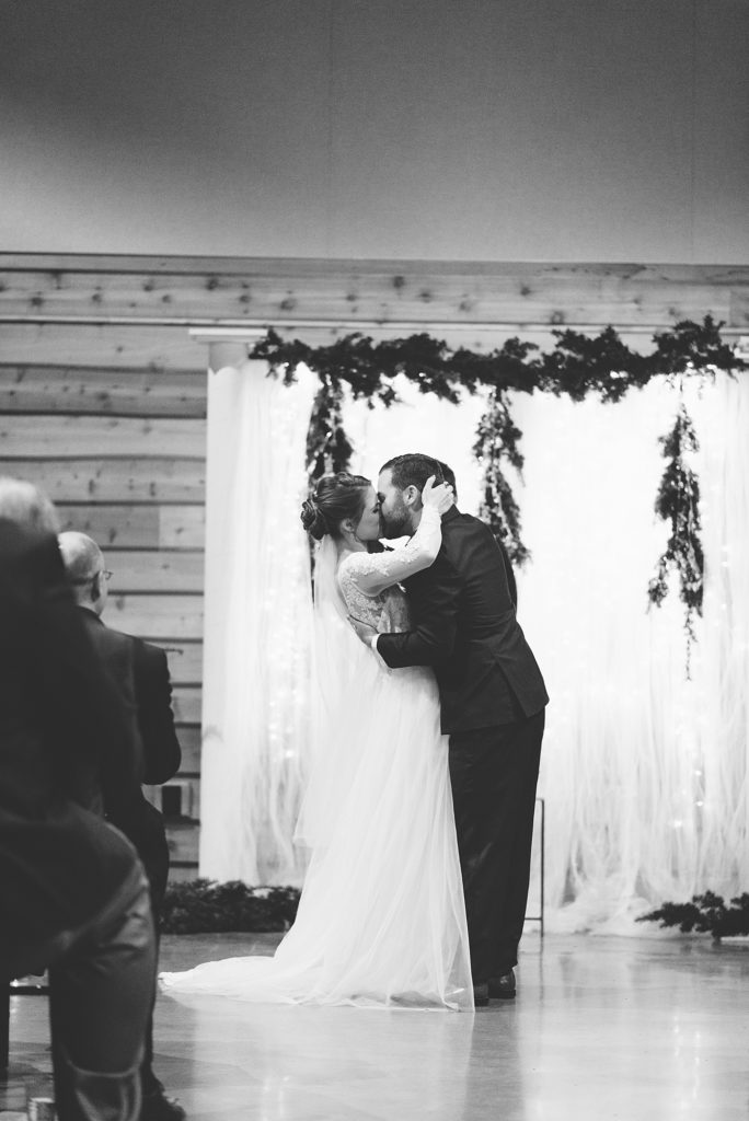A black and white photo of a husband and wife kissing when they announced as husband and wife at the barn at sycamore farms in Arrington Tennessee by Dolly DeLong Photography