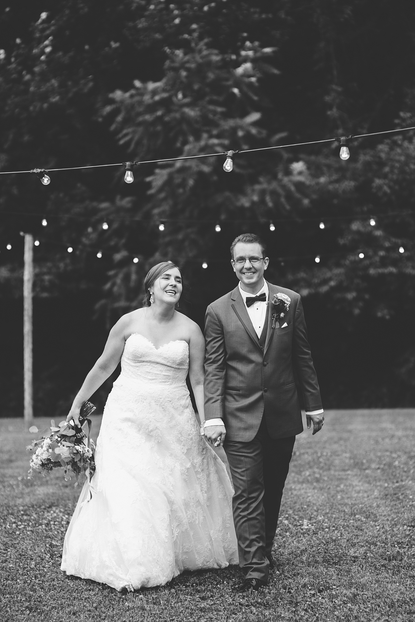 A black and white portrait of a bride and groom walking towards the camera for their summer wedding at Hidden Creek farm weddings by Dolly DeLong PHotography