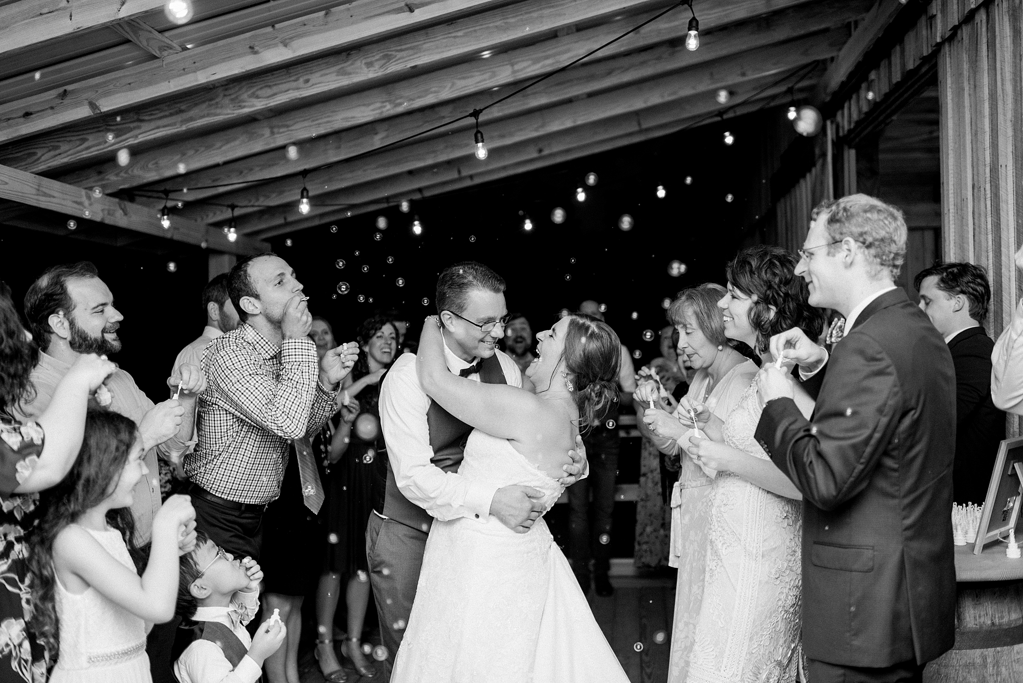 Black and White portrait of a husband and wife kissing at a bubble exit at Hidden Creek Farm Weddings at Dolly DeLong Photography