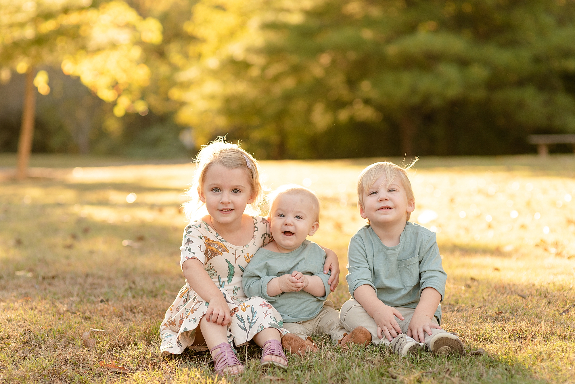 three siblings sitting in park for family portraits in Nashville by Dolly DeLong