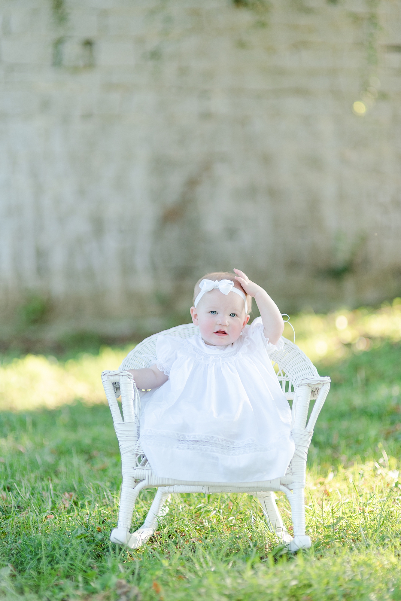 1 year old girl sitting in a wicker chair at Ravenswood Mansion and looking at camera in Nashville