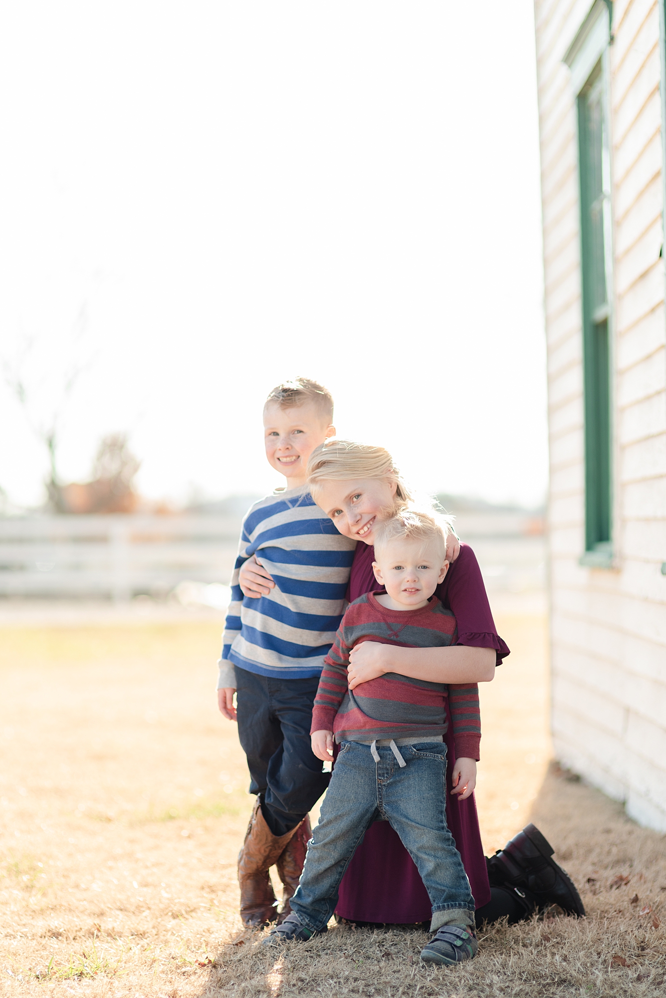 three siblings standing and smiling at camera for family portraits