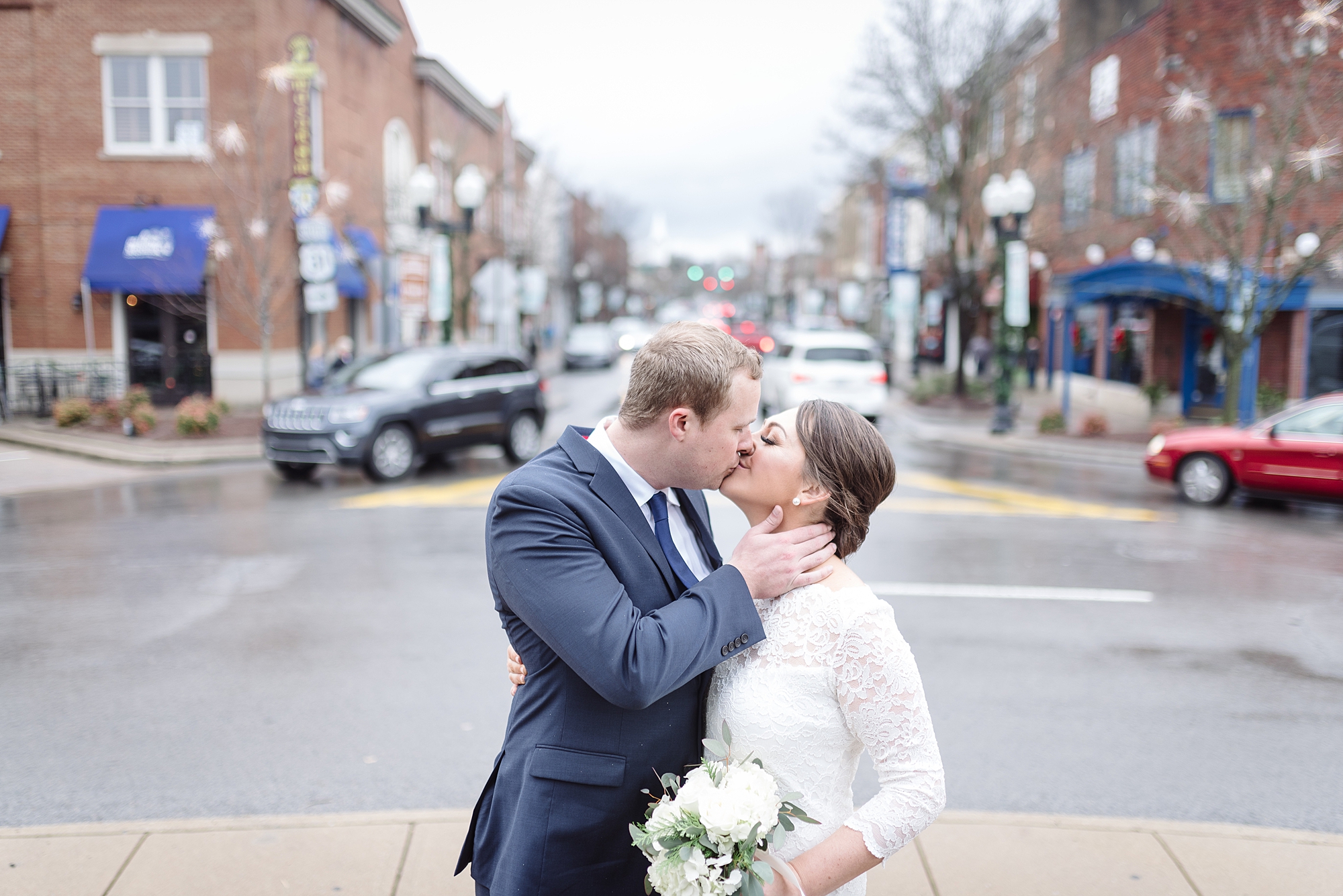 a man and a woman are kissing in downtown franklin, Tennessee for their new year's eve wedding winter wedding with Dolly DeLong Photography