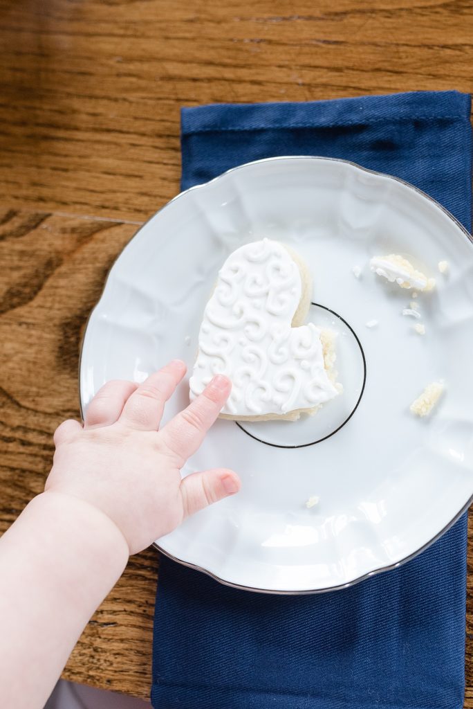 chubby baby hands grabbing white cookie for valentines day