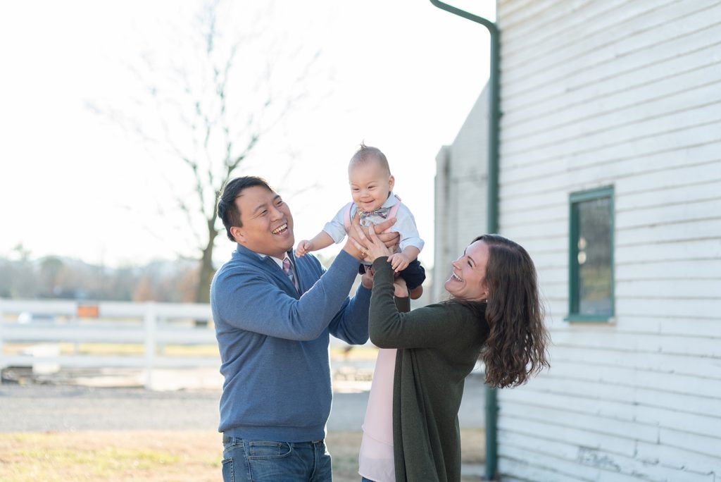 a joyful photo of a mom and dad holding their baby boy in franklin Tennessee for family photography portraits with Dolly DeLong
