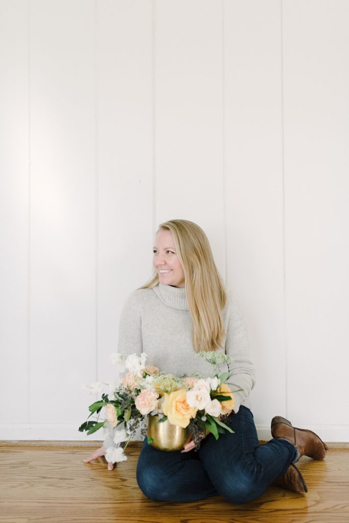 picture of a woman sitting on a wooden floor looking off and smiling for her branding session for a florist business in Nashville