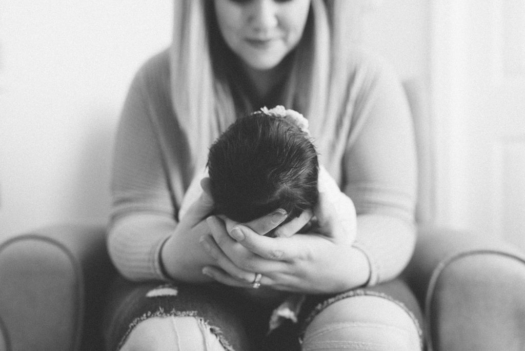 a black and white photo of a new mom holding her baby girl by nashville newborn and family photographer dolly delong photography