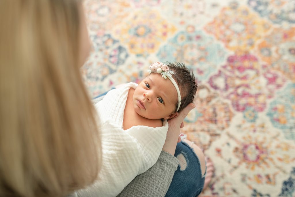 a newborn baby girl being held by her mom and she is looking up at her mom by nashville family and newborn photographer Dolly DeLong Photography