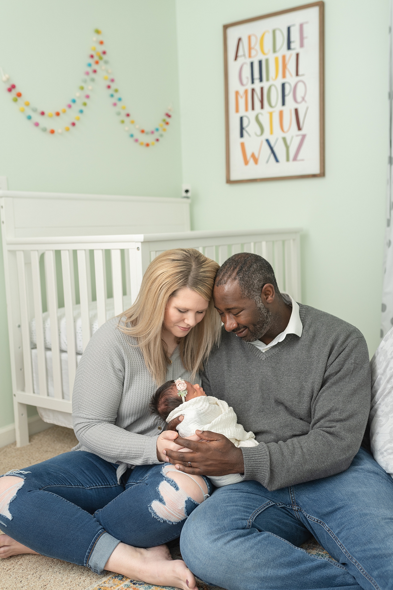 a new mom and dad are holding their newborn baby girl for a family home session with nashville family and newborn photographer dolly delong photography