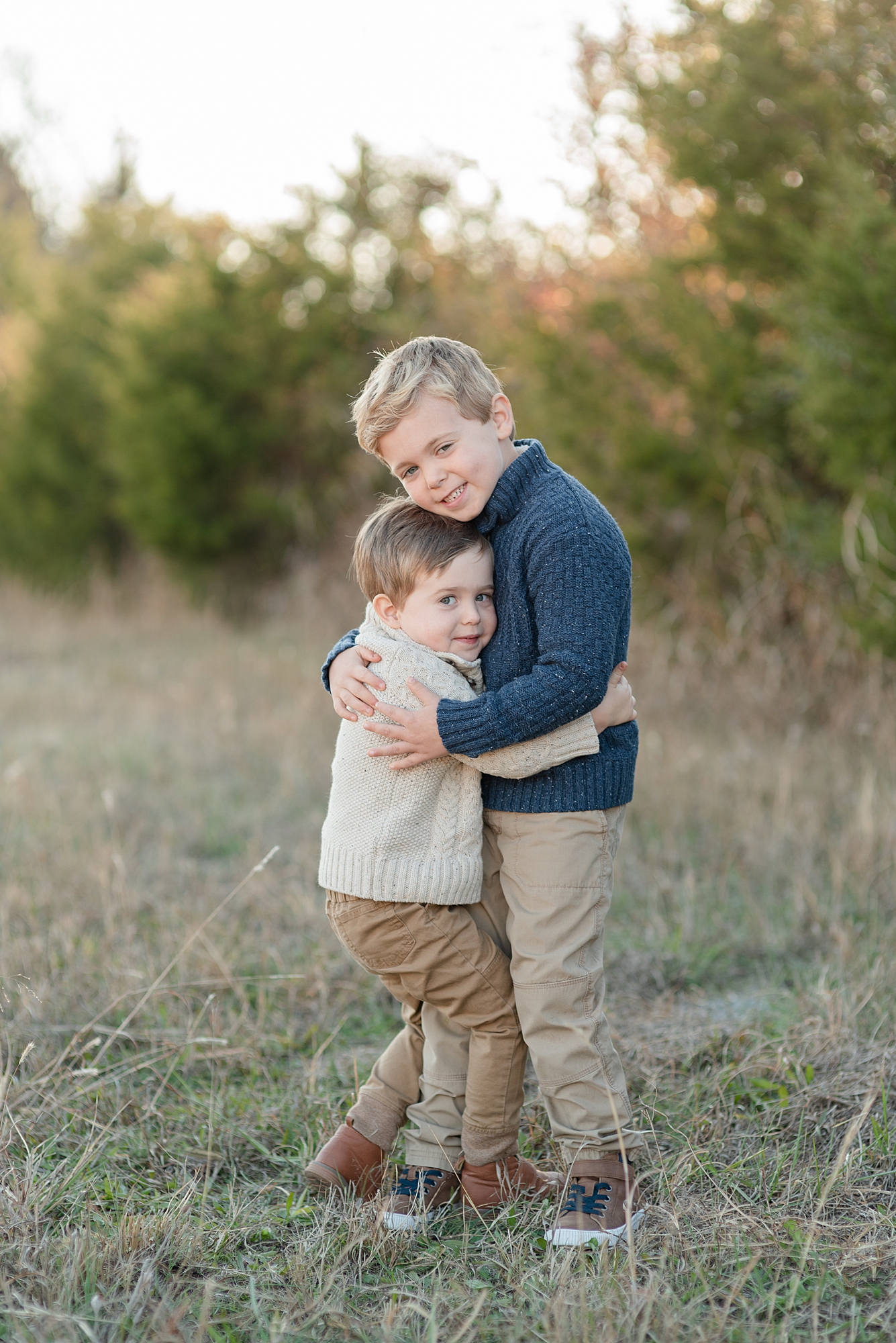 Two brothers are hugging and smiling in a field for family pictures by Nashville family photographer Dolly DeLong Photography