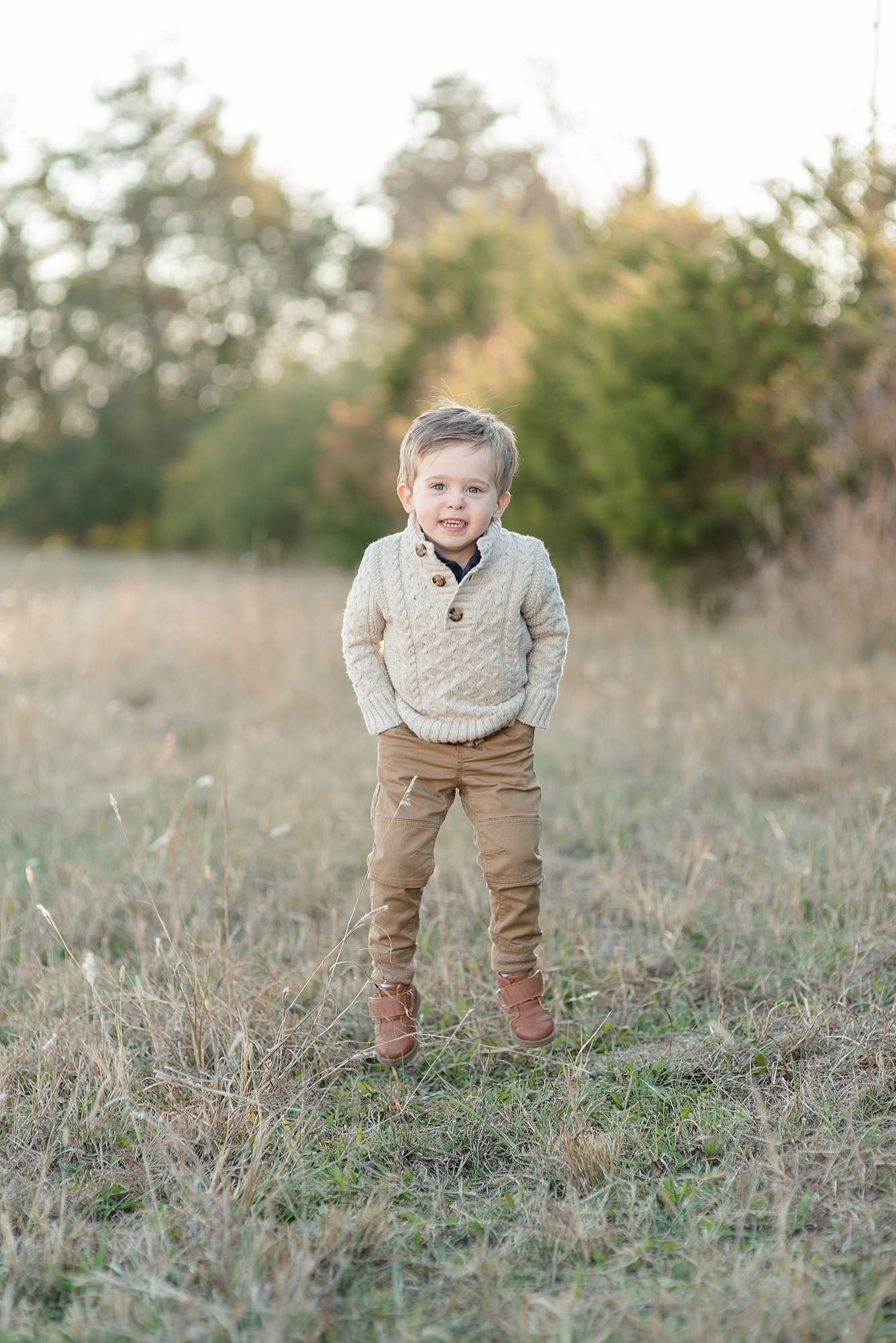 a little boy is standing with his hands in his pockets and smiling at the camera for his family pictures with Nashville family photographer Dolly DeLong Photography