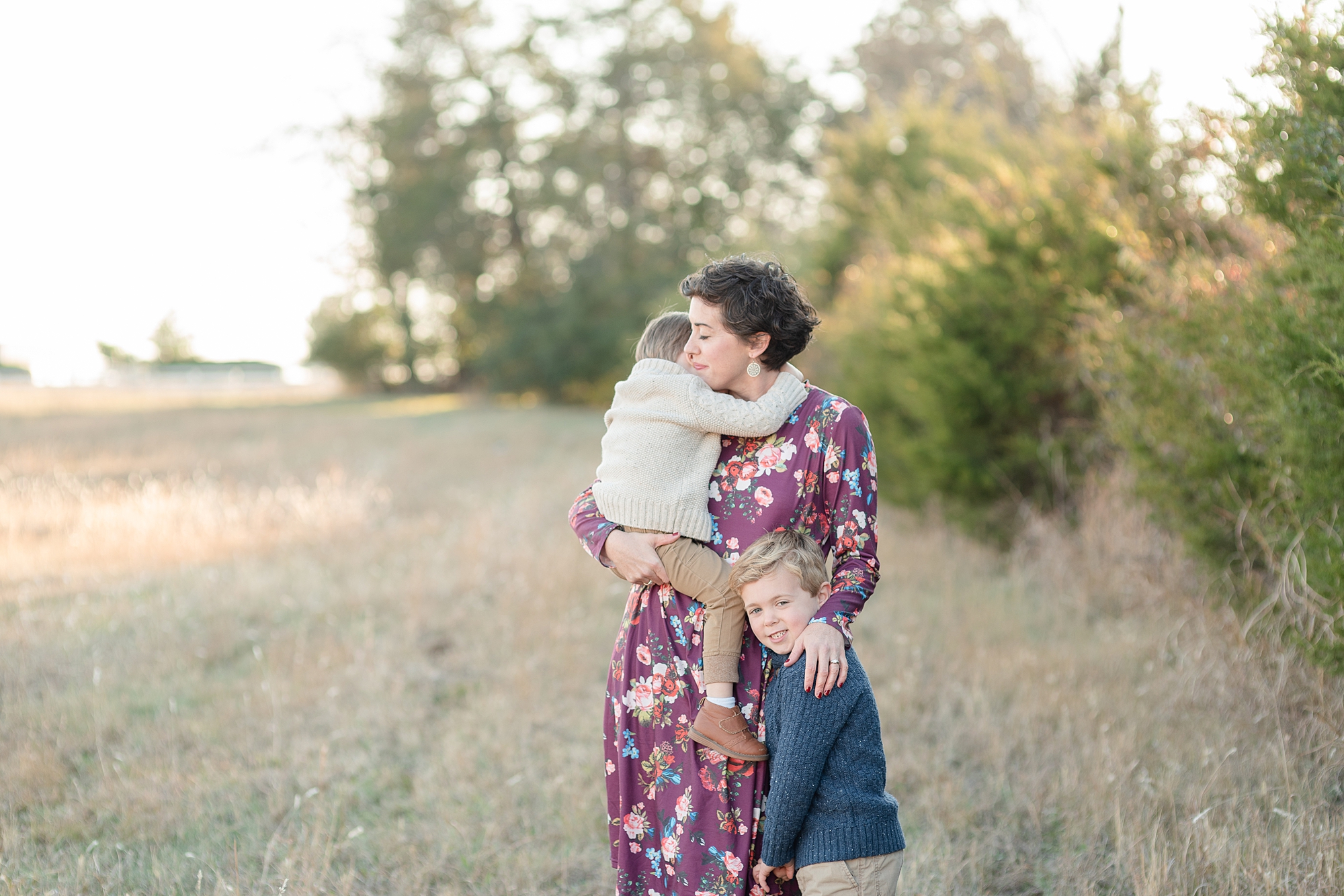 a mother is hugging her youngest son and her oldest son is standing beside her leg hugging her on the side portraits by Nashville family photographer Dolly DeLong Photography