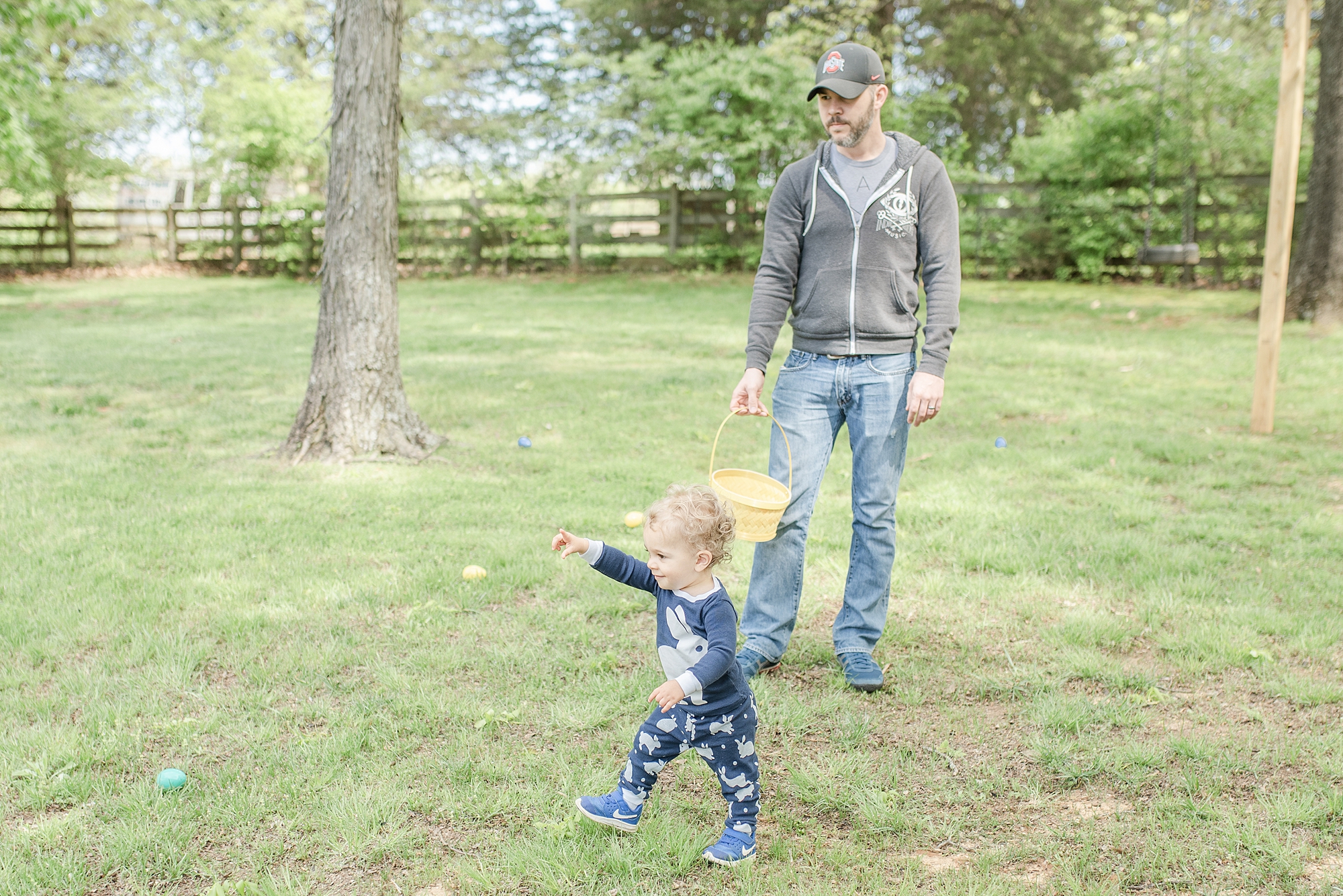 image of a little toddler hunting for easter eggs with his father in Nashville, TN by Nashville Family Photographer Dolly DeLong Photography