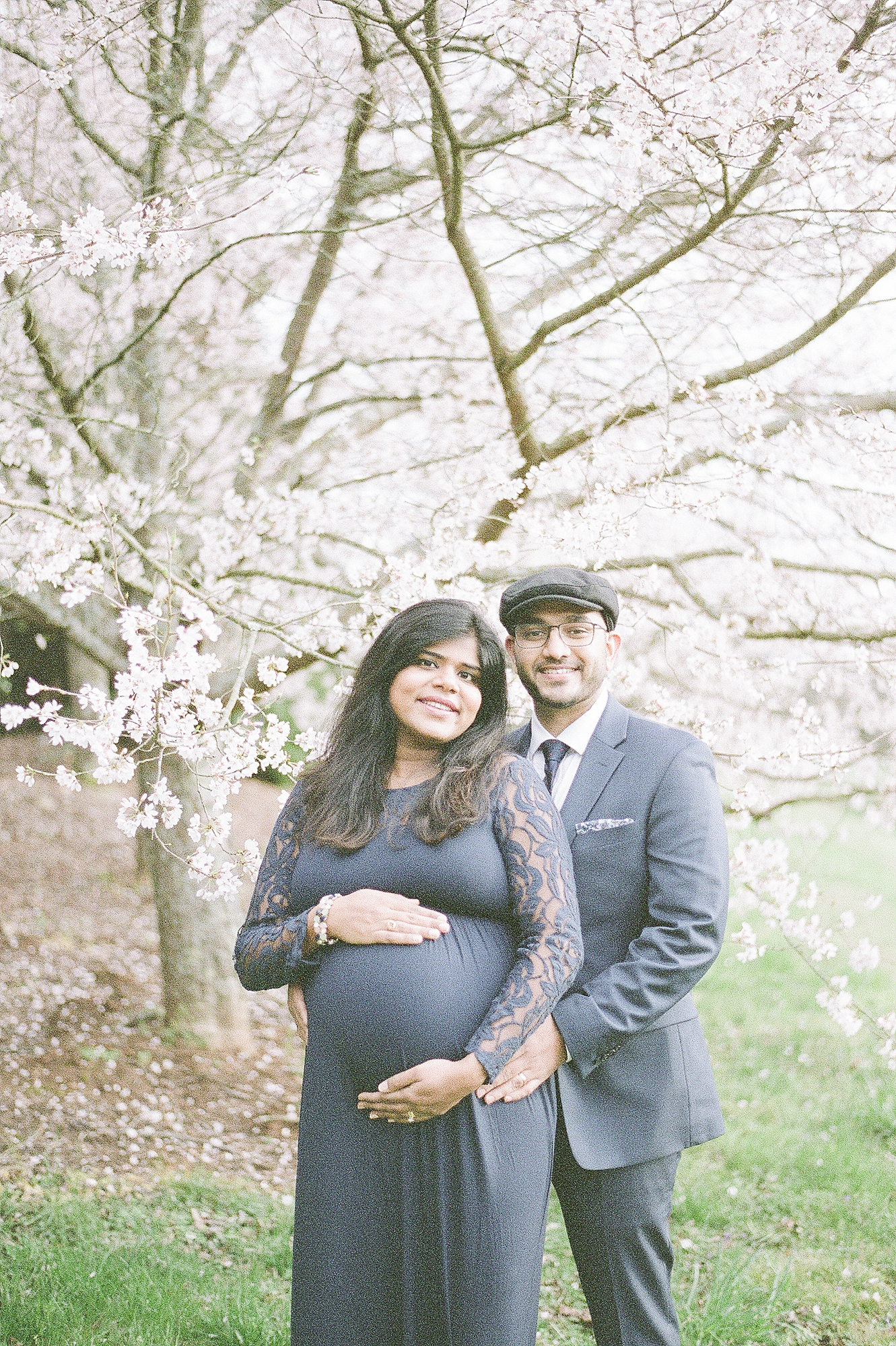 an indian couple are having their maternity session done on fuji400h film by Nashville family photographer Dolly DeLong Photography in Spring near spring blossom trees