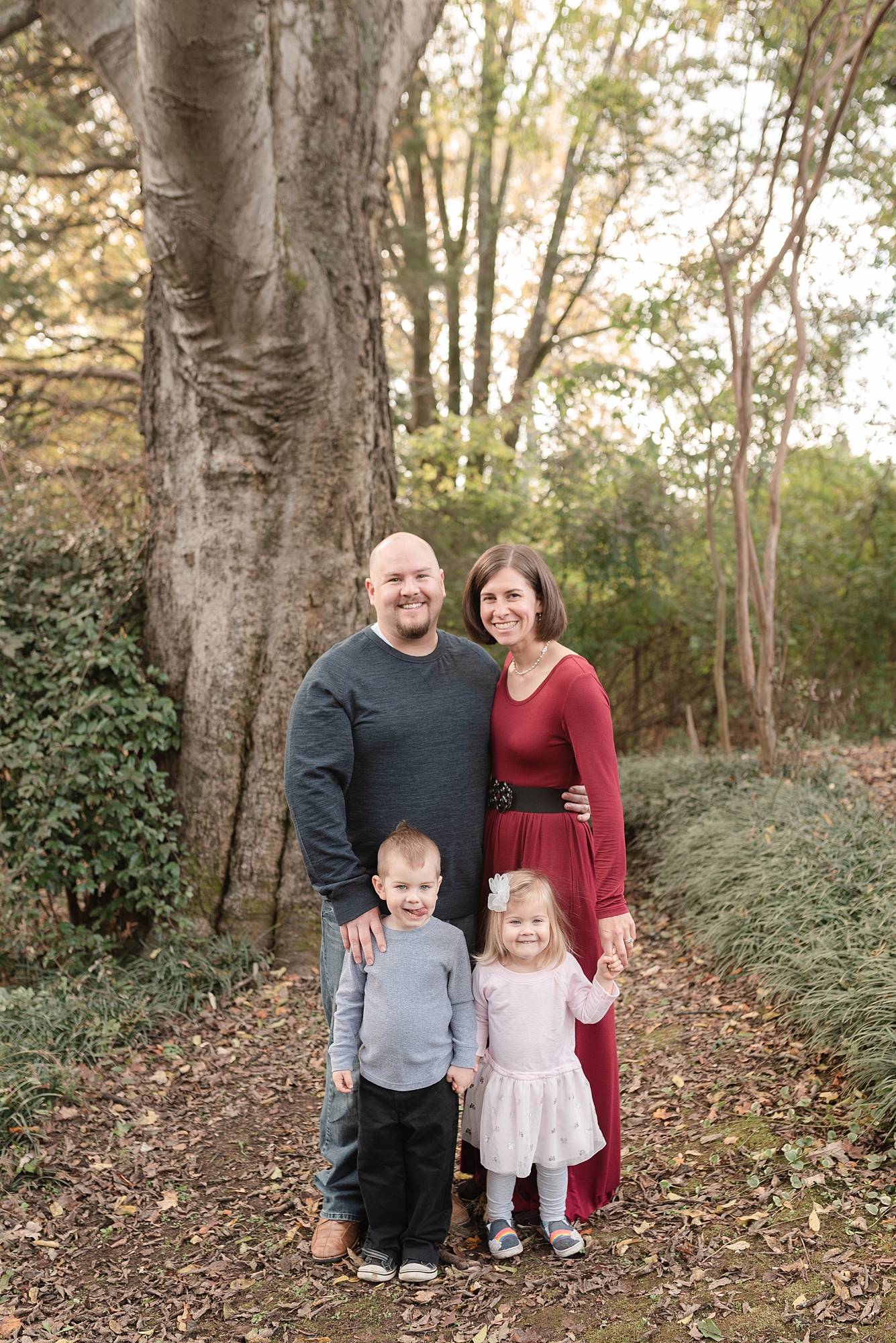 family of four stand and looking at camera and smiling at historic stone hall in Nashville, TN by Nashville family photographer Dolly DeLong Photography