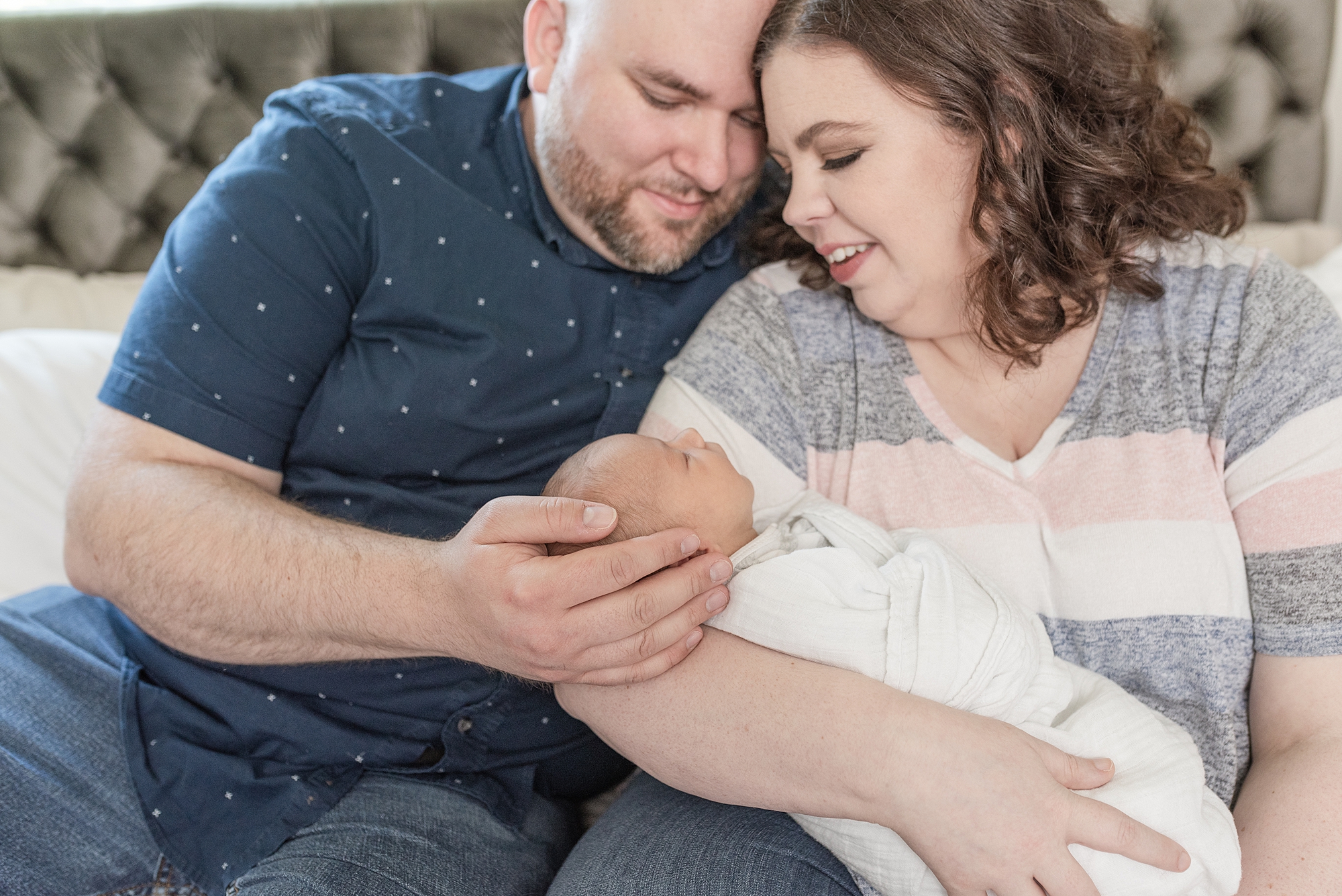 a mom and dad are holding their newborn baby boy and smiling at him by nashville family photographer Dolly DeLong Photography