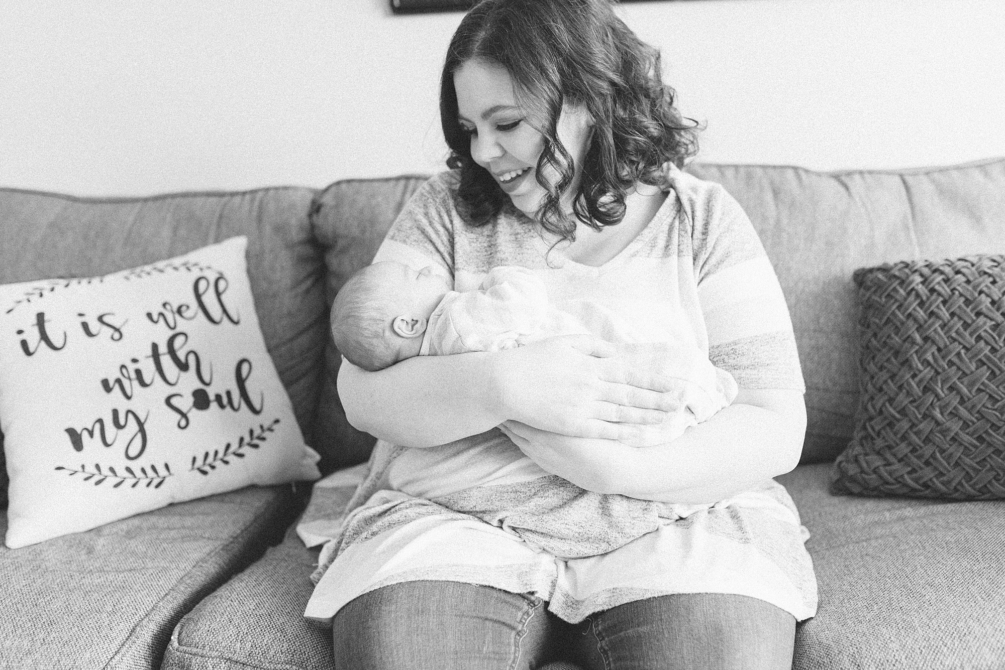 a black and white photo of a mom holding her newborn baby boy and she is smiling by nashville family photographer Dolly DeLong Photography