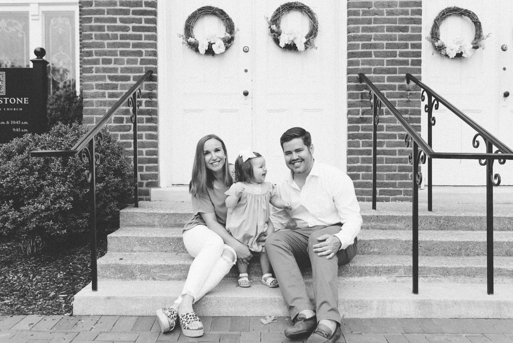 black and white image of a family of three sitting on church steps in downtown franklin tennessee by Nashville Family Photographer Dolly DeLong Photography