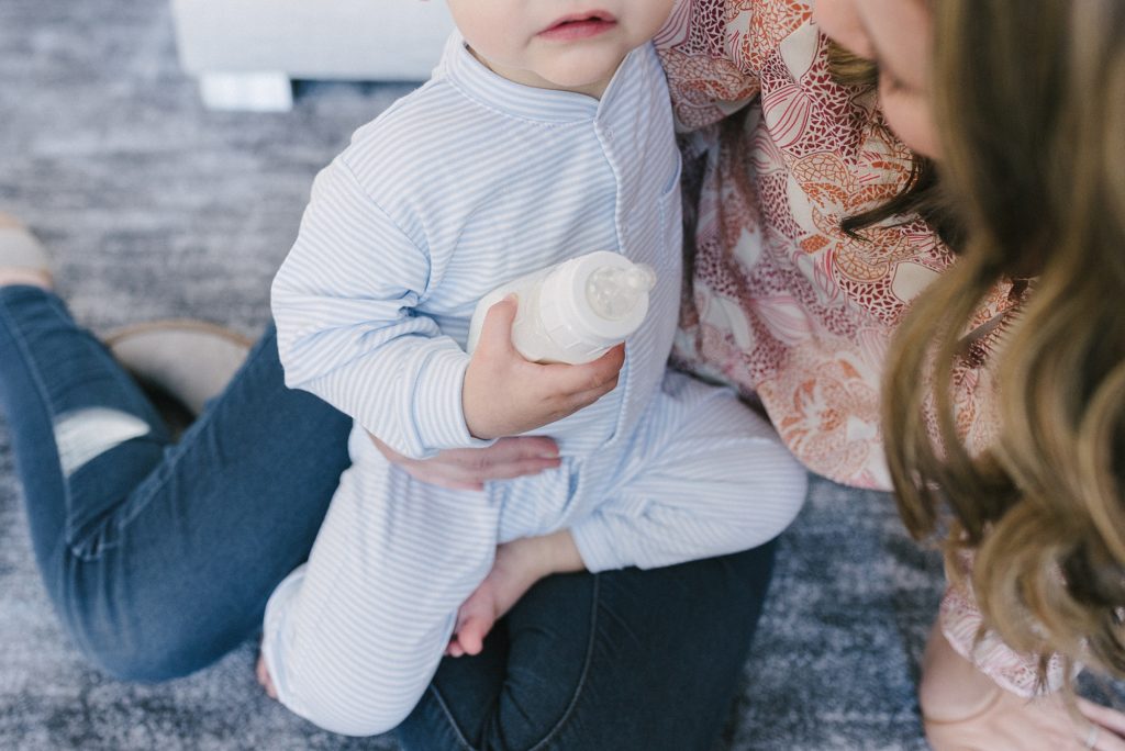picture of a boy holding a bottle in his hands while being held by his mom by Nashville branding photographer Dolly deLong Photography