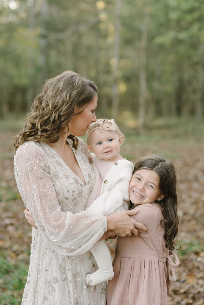 Mother holding her baby daughter and being hugged by her oldest daughter for family photos by Nashville Family Photographer Dolly DeLong Photography