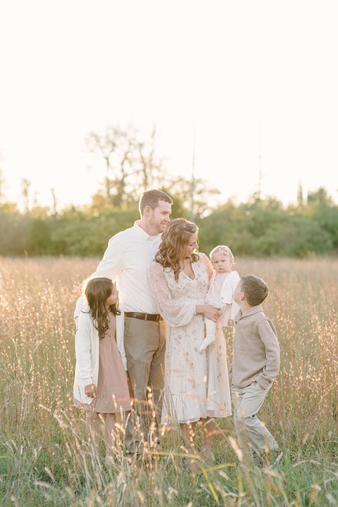 a family of five walking in a tall grassy field in Nashville by Nashville Family Photographer Dolly DeLong Photography