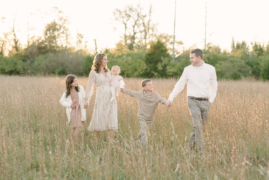 a family of five walking in a tall grassy field in Nashville by Nashville Family Photographer Dolly DeLong Photography