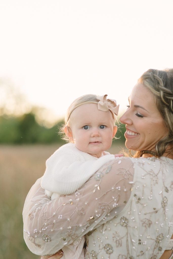 a mother holding her almost one year old daughter for family photos in the sunset by Nashville Family Photographer Dolly delong photography